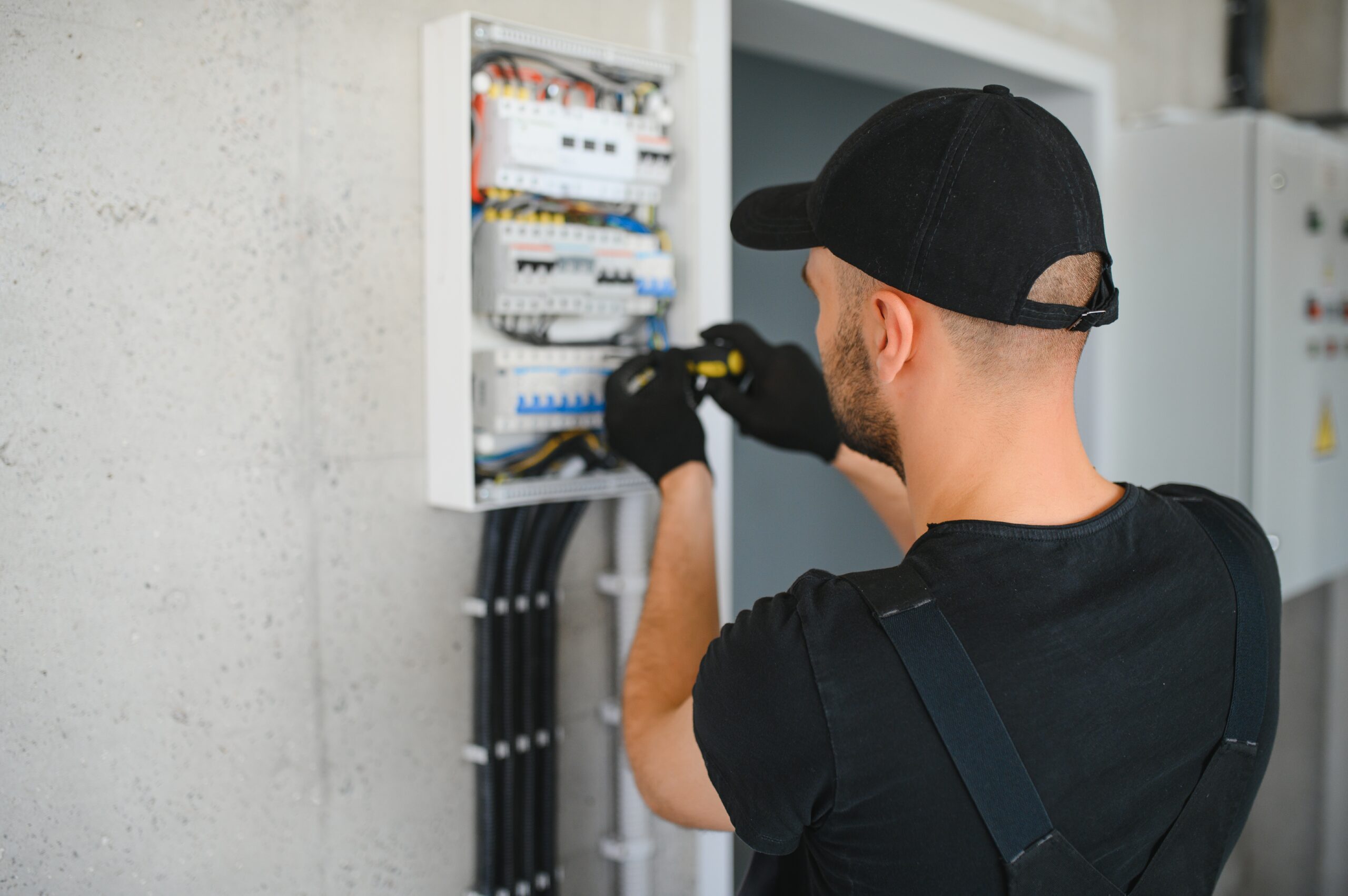 male electrician working in a switchboard with fuses